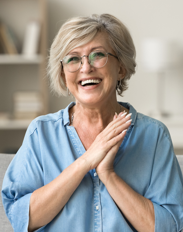 old woman clasping her hands together